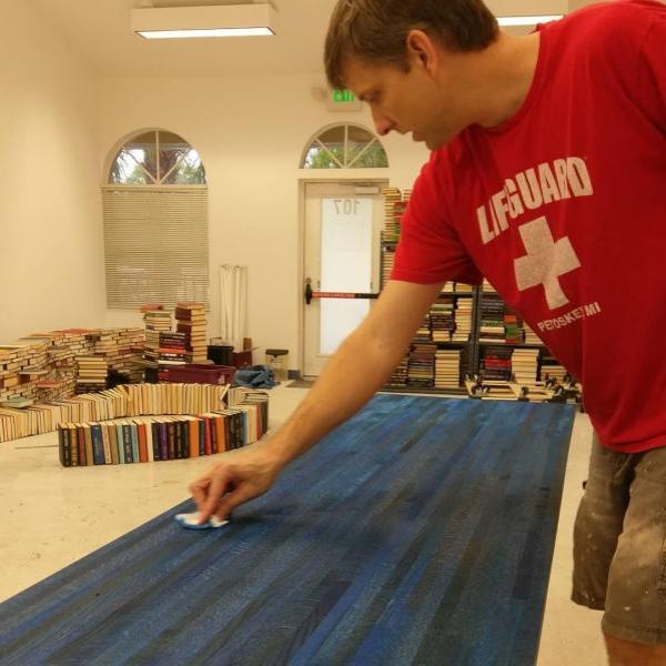 Scott Hill wipes off the newly-stained blue wooden counter, used for checkout in the new Sandman Books location.  Book Arch in Sandman Books Punta Gorda Florida. Florida Tourism Tourist Local Art Artist Artwork Fantasy Harry Potter Beauty and the Beast Disney Wedding Photography Unconventional Unique Venue Sell Used New Books Bookstore Bookshop Library  