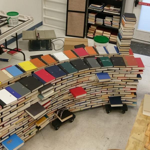 Books with holes drilled in them sit stacked together, waiting to be used in the construction of the book arch.  Book Arch in Sandman Books Punta Gorda Florida. Florida Tourism Tourist Local Art Artist Artwork Fantasy Harry Potter Beauty and the Beast Disney Wedding Photography Unconventional Unique Venue Sell Used New Books Bookstore Bookshop Library  