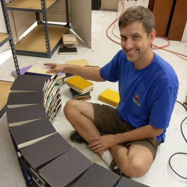 Scott Hill smiles for the camera while constructing the book arch. Book Arch in Sandman Books Punta Gorda Florida. Florida Tourism Tourist Local Art Artist Artwork Fantasy Harry Potter Beauty and the Beast Disney Wedding Photography Unconventional Unique Venue Sell Used New Books Bookstore Bookshop Library  